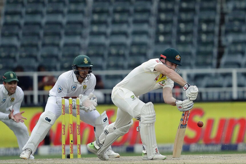 Shaun Marsh blocks the ball while Quinton de Kock watches on from behind the stumps.