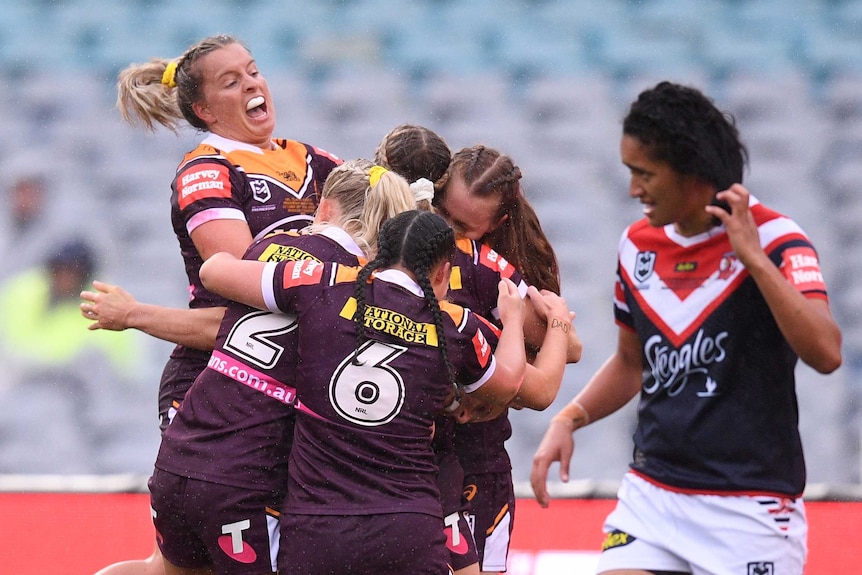 Brisbane Broncos women's players hug and smile at each other in a group