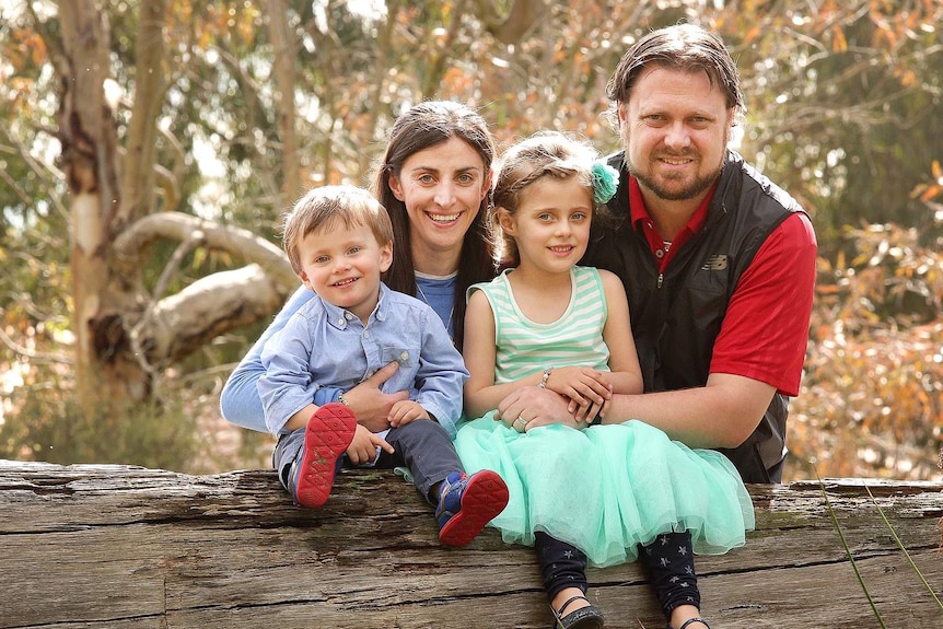 Lisa Briggs sits on a log with her family