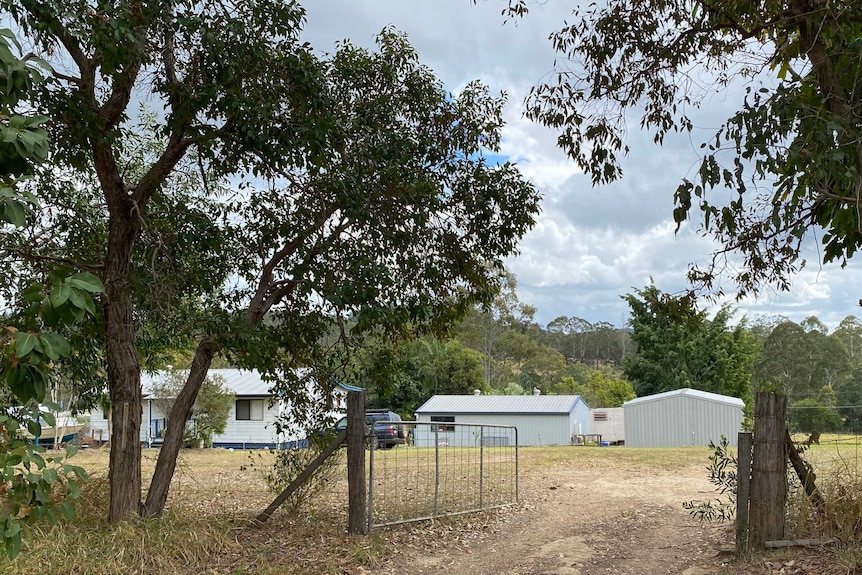 A house in the distance with a drive way and trees.