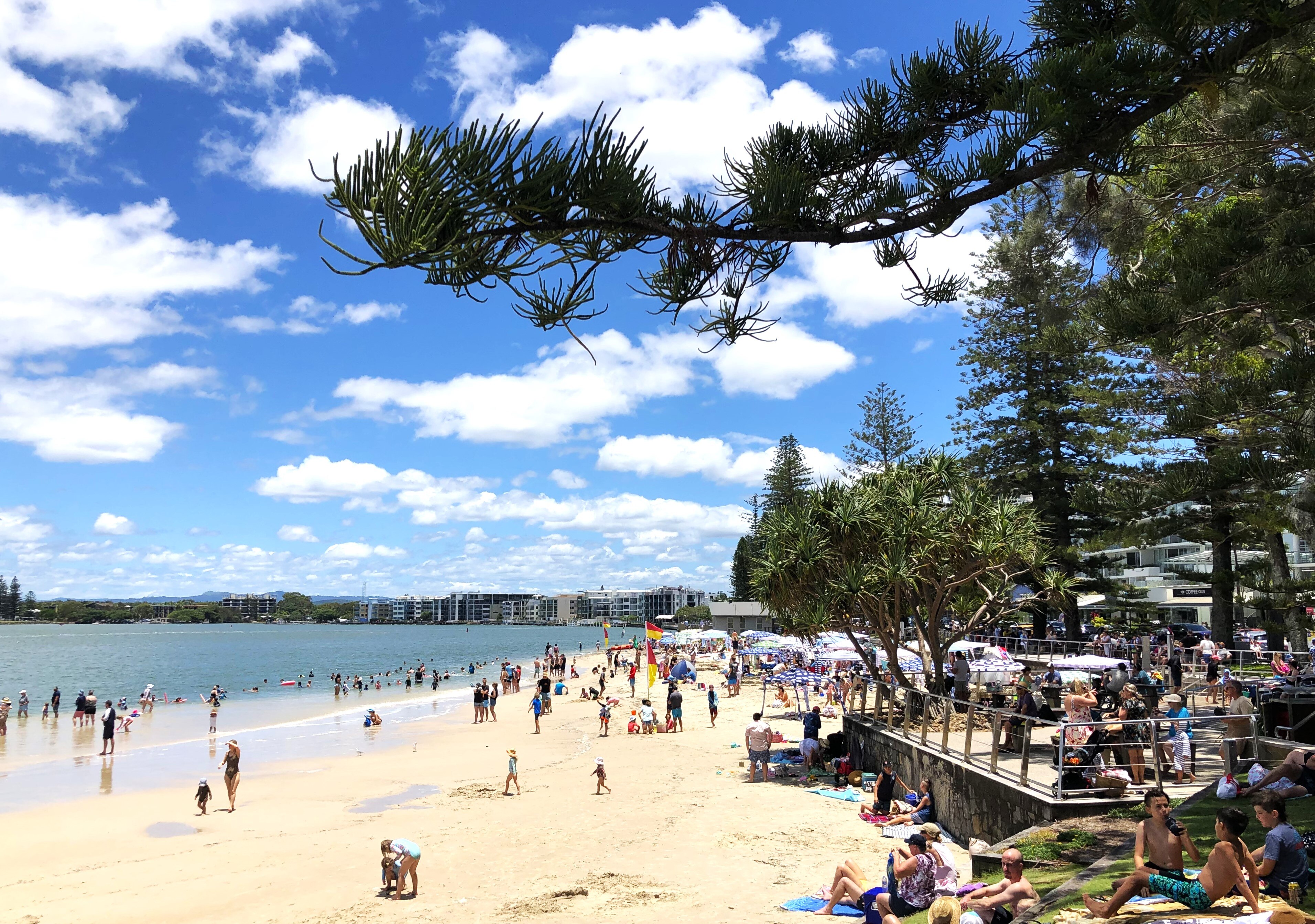 Crowds of people on the sand and in the water at the beach on a sunny day