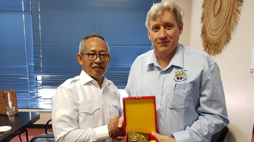 Two men presenting a trophy in an office.