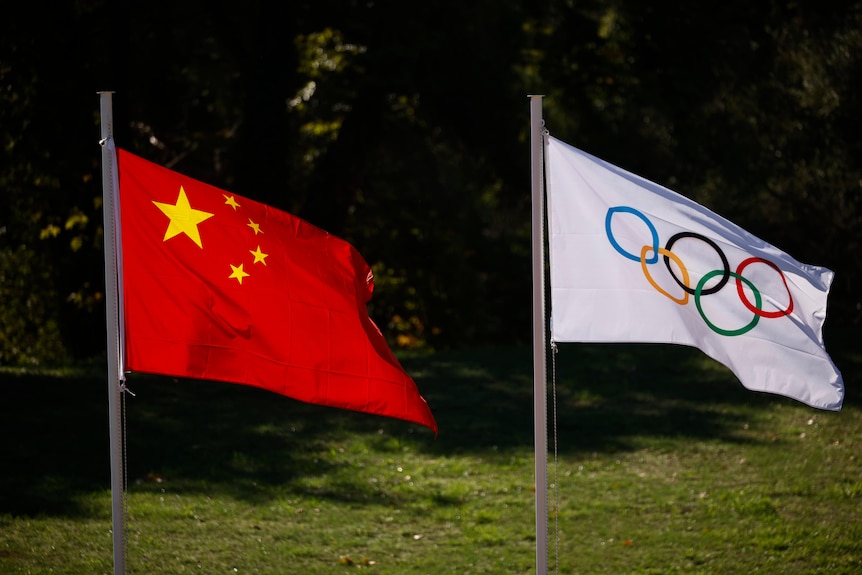 The flags of China and the International Olympic Committee flying on a flagpole