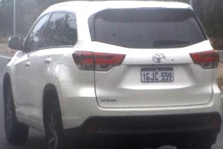 A white four-wheel-drive car driving on the road.