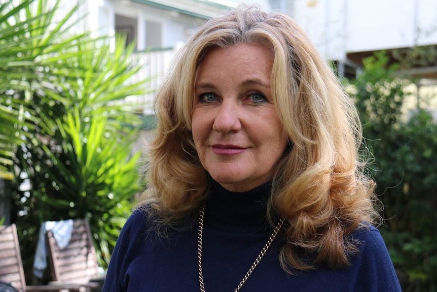 Leigh Bird looks towards the camera standing outside her house.