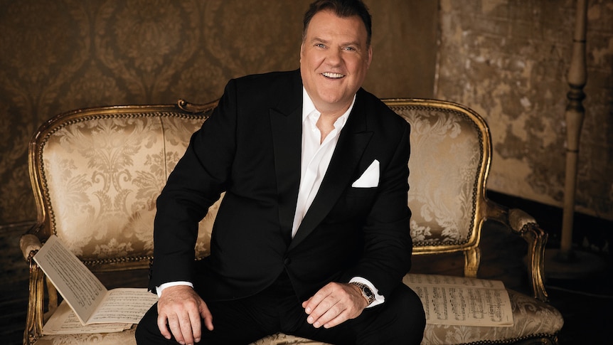 Bryn Terfel sits on a gold chair surrounded by sheet music