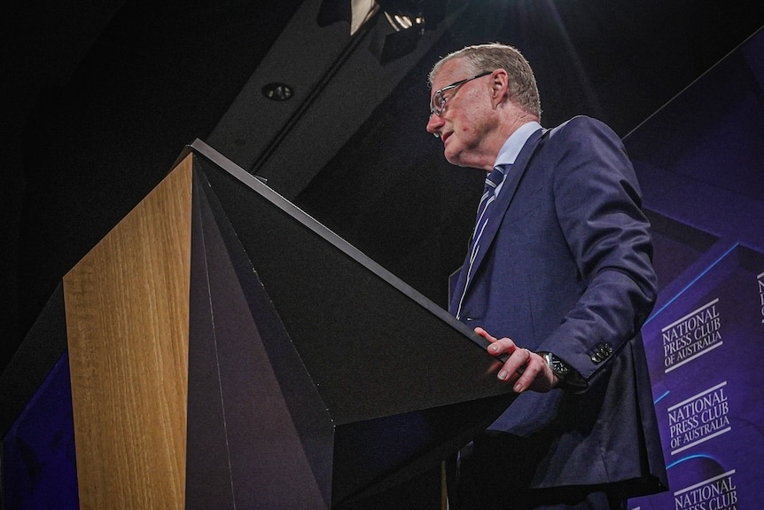 Philip Lowe stands at a podium, speaking at the National Press Club