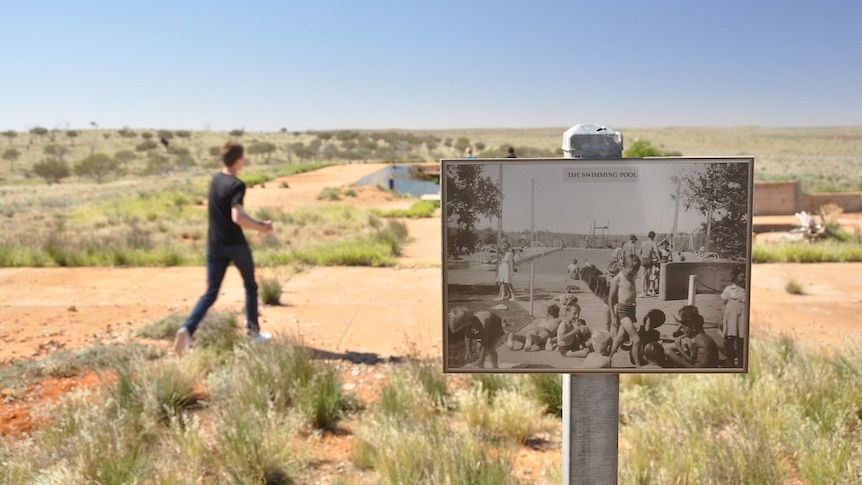A black and white photo mounted on a pole in the outback shows a poll scene 50 years ago.