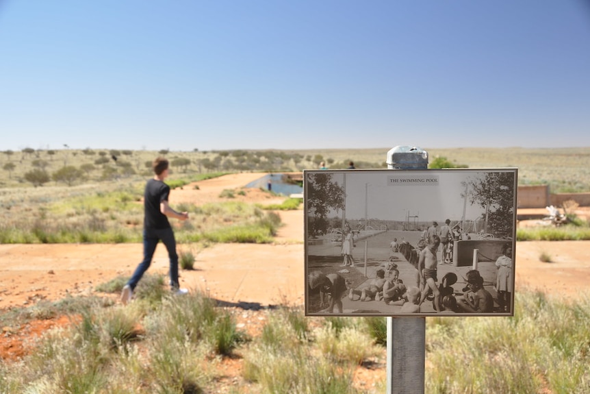 A black and white photo mounted on a pole in the outback shows a poll scene 50 years ago.