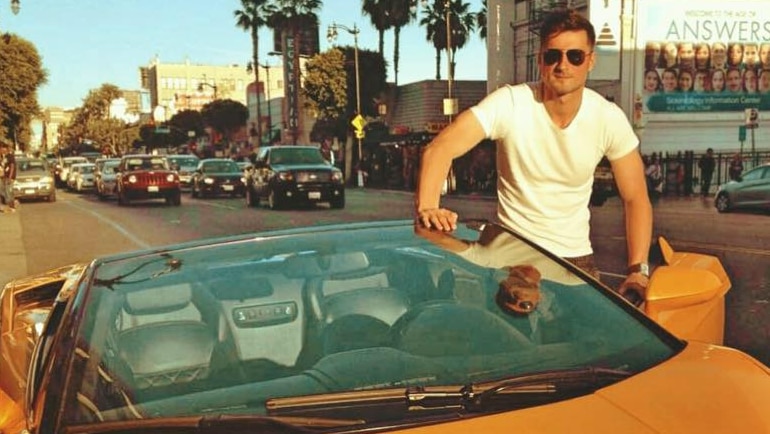 Bahtiyar Duysak is pictured with an orange lamborghini in Los Angeles