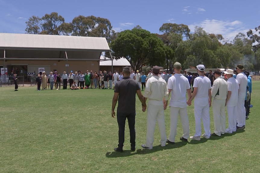 Men stand in line at a cricket oval