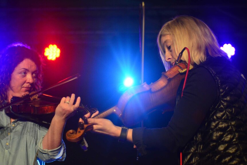 The Shamrock Sheilas, Lousie Phelan and Mary McEvilly-Butler play fiddles on a stage.