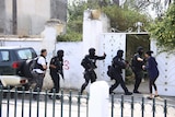 Tunisian anti-terrorism brigade personnel enter a house to take position