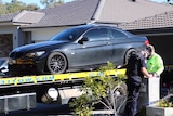 A black BMW coupe being placed on a tow truck by police