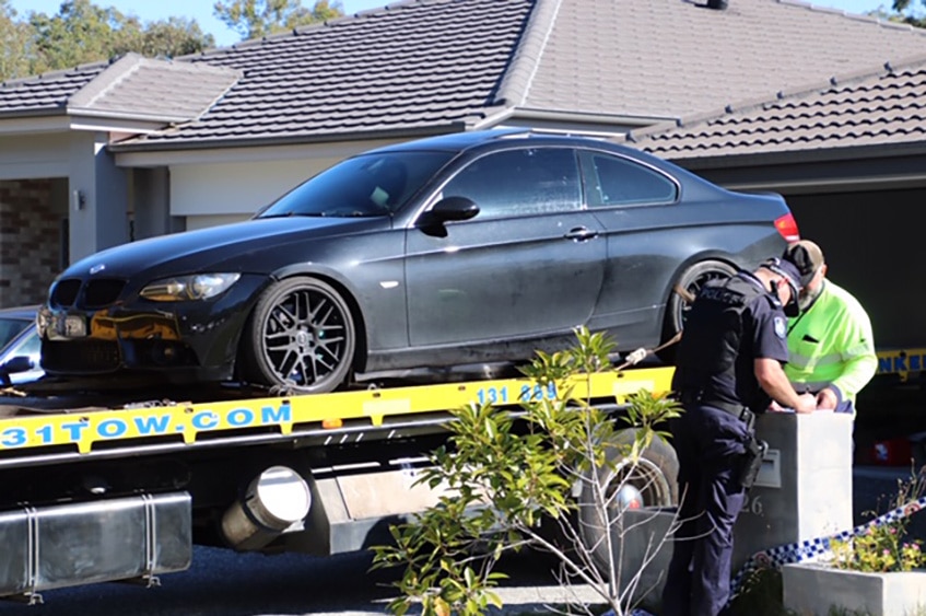 A black BMW coupe being placed on a tow truck by police