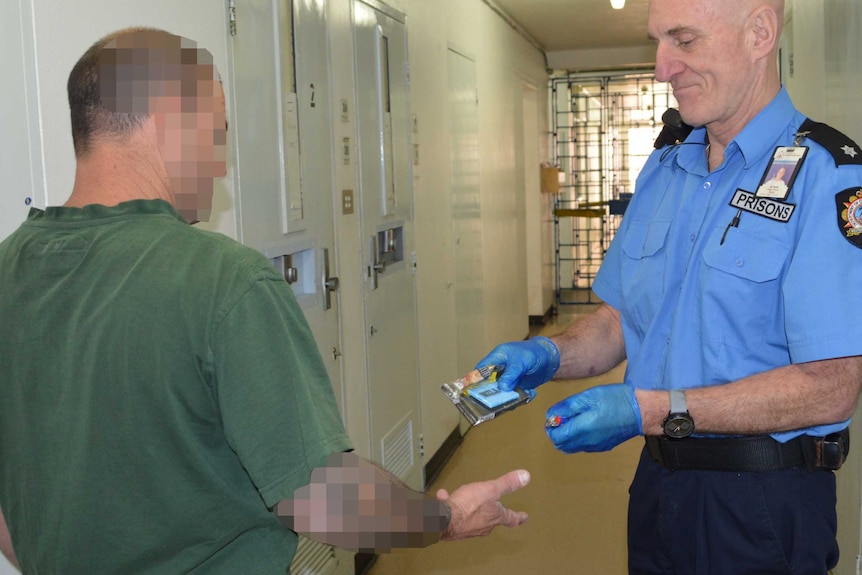 A prison officer gives an inmate his cigarettes after a drug search inside Bunbury Prison.