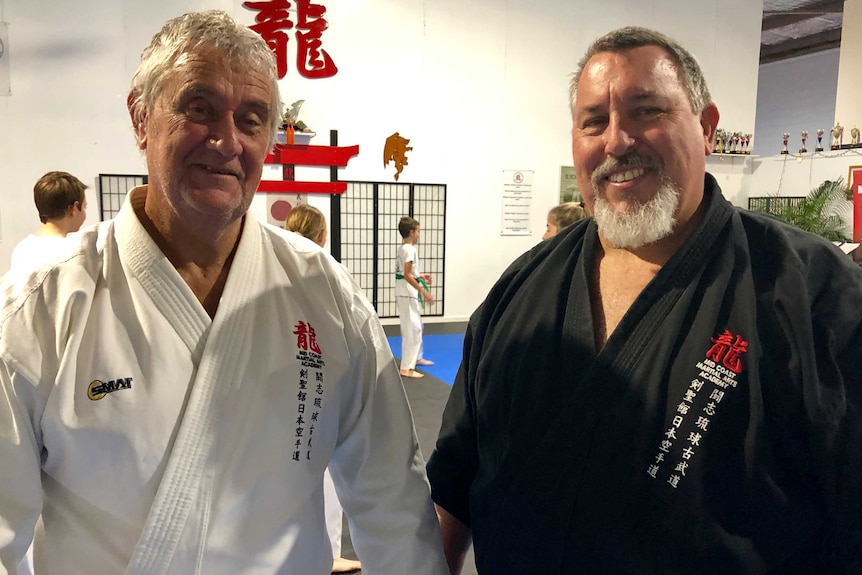 Two martial arts instructors standing together in a martial arts studio.