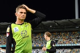 Sydney Thunder player Chris Green scratches his head while fielding in a Big Bash League game at the Gabba. The lights are out.