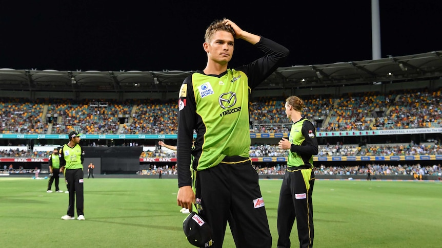 Sydney Thunder player Chris Green scratches his head while fielding in a Big Bash League game at the Gabba. The lights are out.