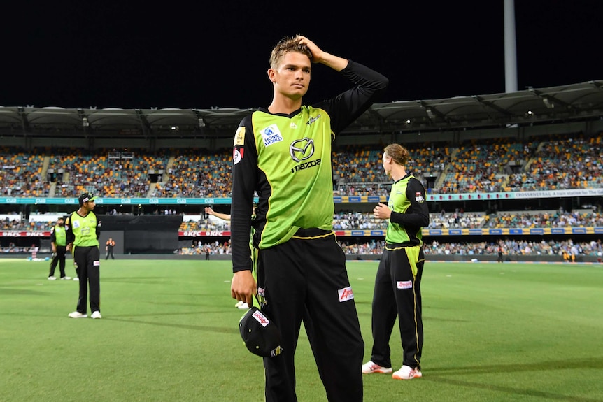 Sydney Thunder player Chris Green scratches his head while fielding in a Big Bash League game at the Gabba. The lights are out.