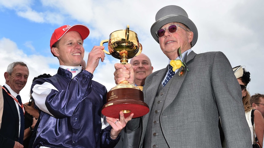 Jockey Kerrin McEvoy (left) and owner Lloyd Williams hold Melbourne Cup after Almandin's win.