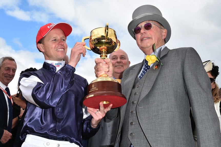 Jockey Kerrin McEvoy and owner Lloyd Williams hold the Melbourne Cup after Almandin wins.
