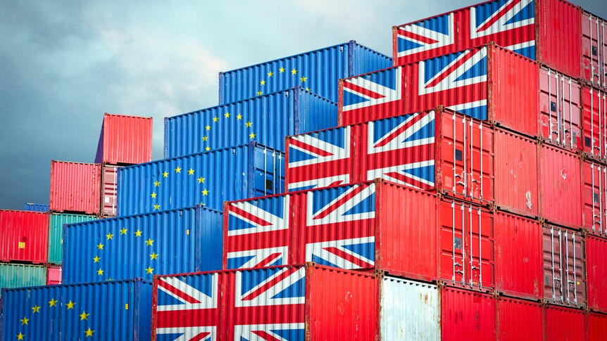 stacked shipping containers bearing the flags of the UK and the EU
