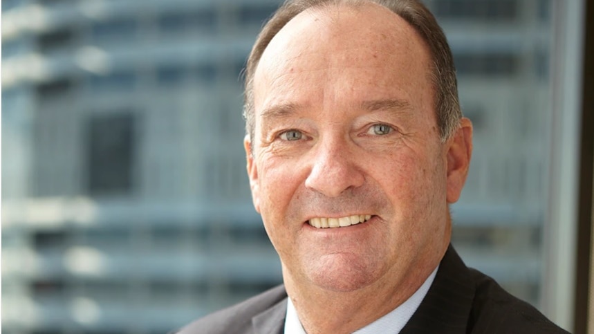 A man in a suit smiles.