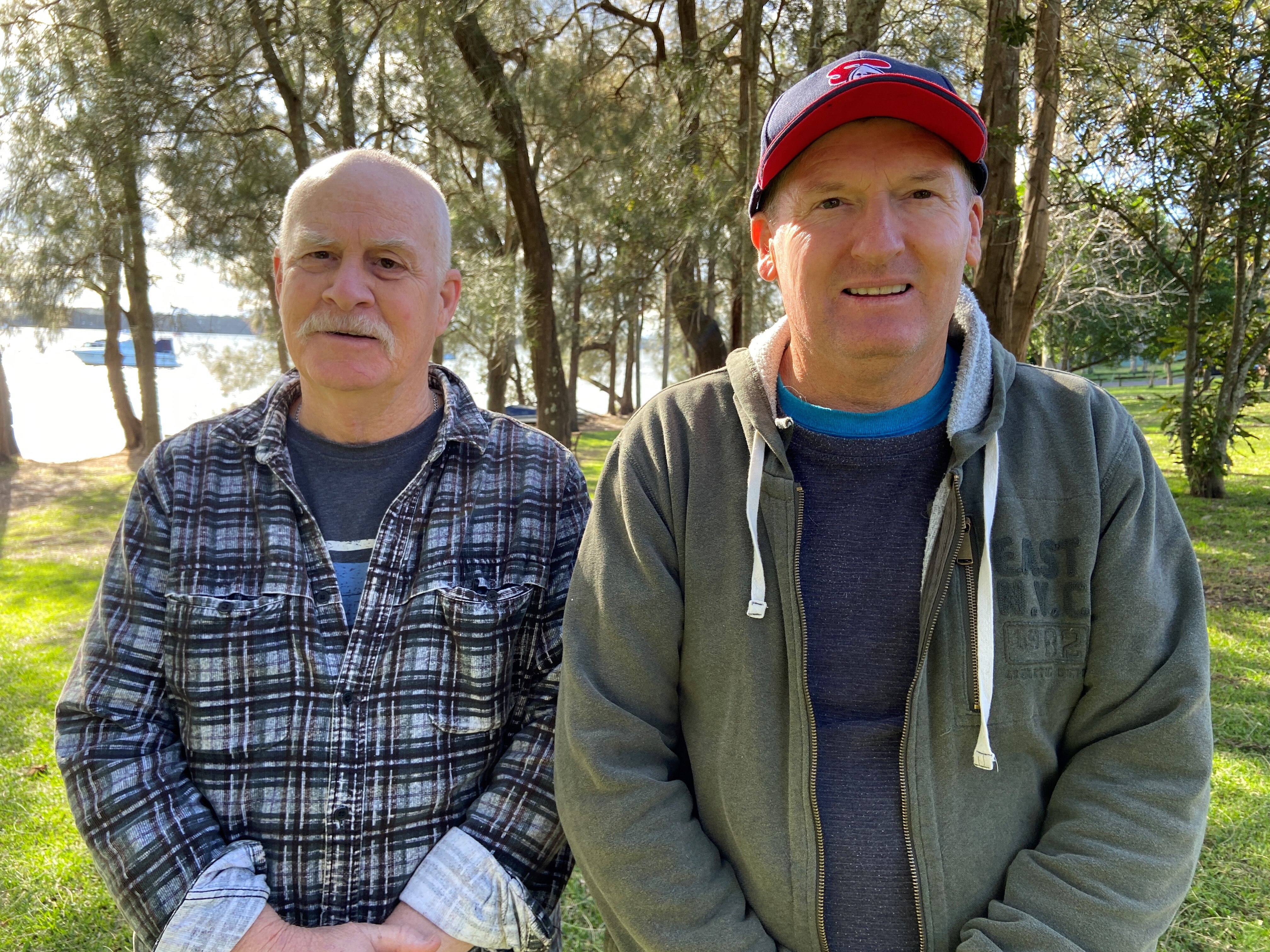 Man wearing fluro yellow polo shirt stands in front of a lake