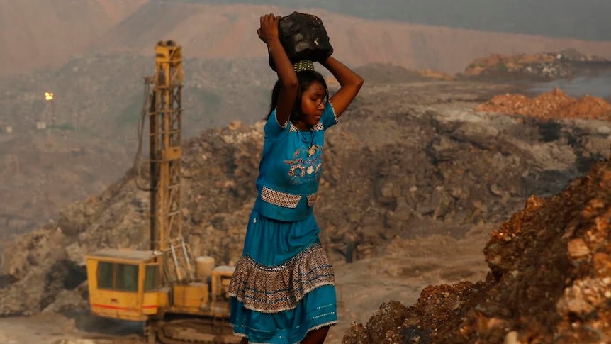 A young (illegal) coal scavenger risks a treacherous path up the side of an open-cut coal mine in eastern India.