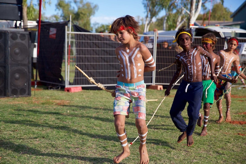 Boys in a line perform Aboriginal cultural dance in Roebourne