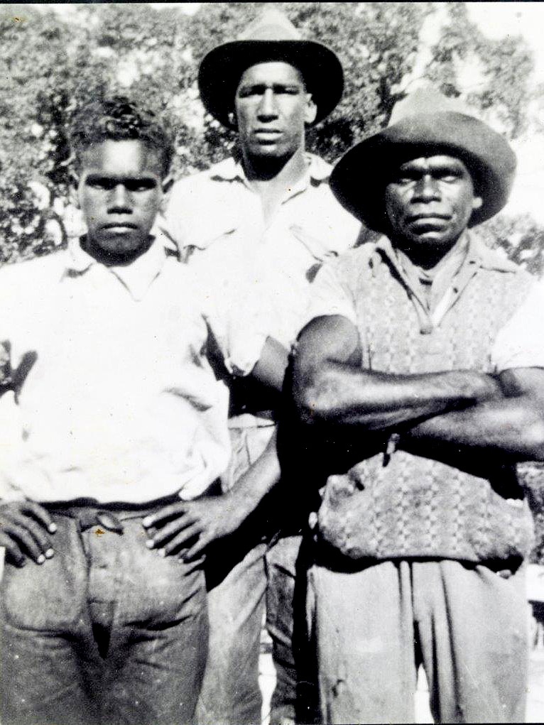 Three men in old fashioned clothes, two at the front and one at the back, one of them has arms folded.