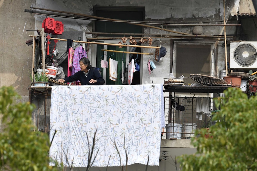 A woman places food out on a balcony to dry at a residential compound in Wuhan.