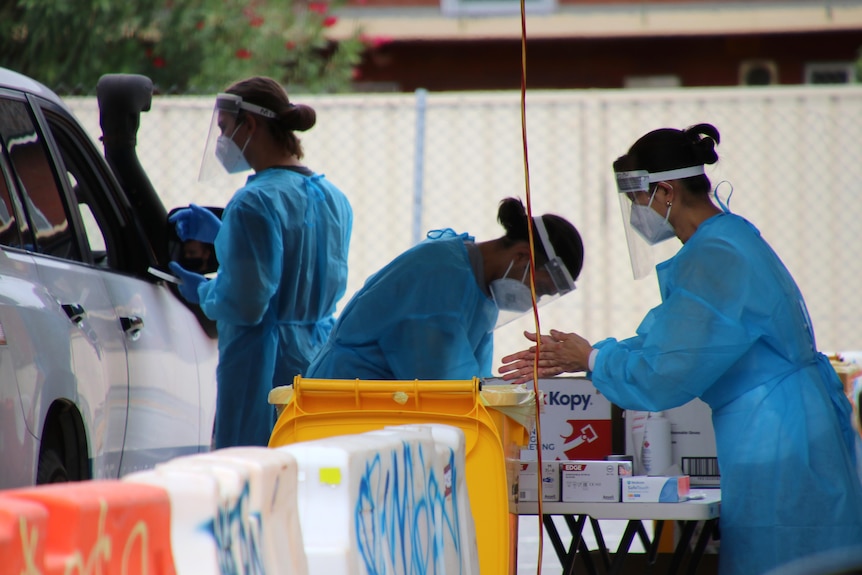 A close-up shot of staff in PPE at a drive-through COVID testing clinic.
