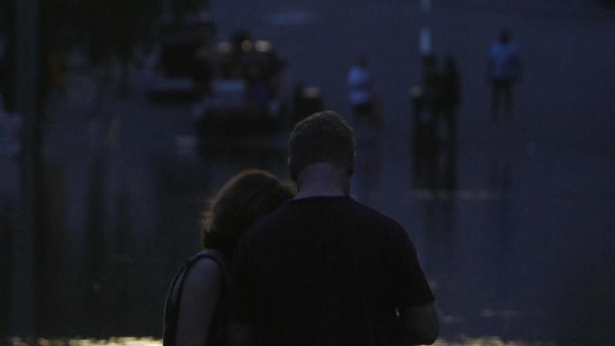 A family is silhouetted in front of a flooded street in the Brisbane suburb of Milton, January 12, 2011.