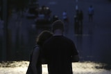 A family is silhouetted in front of a flooded street in the Brisbane suburb of Milton, January 12, 2011.