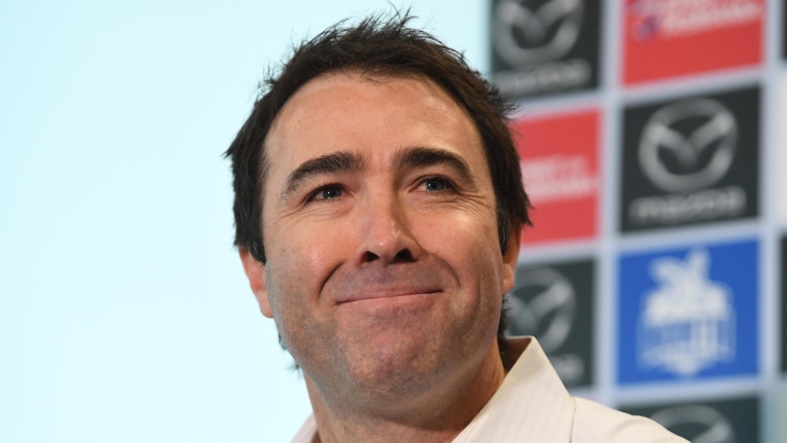 A former North Melbourne AFL coach smiles as he speaks to the media in 2019.