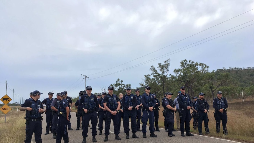 Uniformed police stand in a line over the road leading to the Abbot Point coal terminal.
