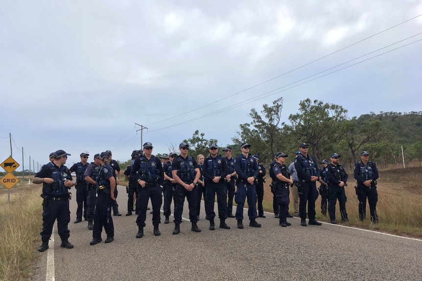 Uniformed police stand in a line over the road leading to the Abbot Point coal terminal.