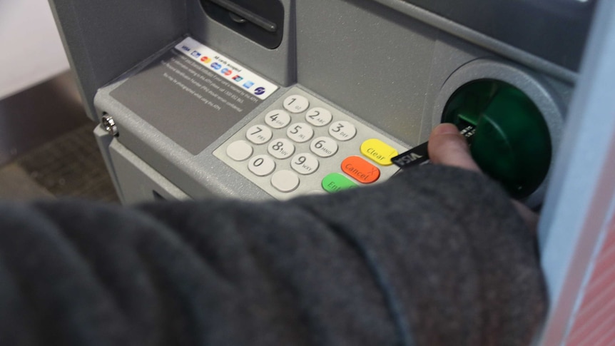 Man puts card into ATM machine