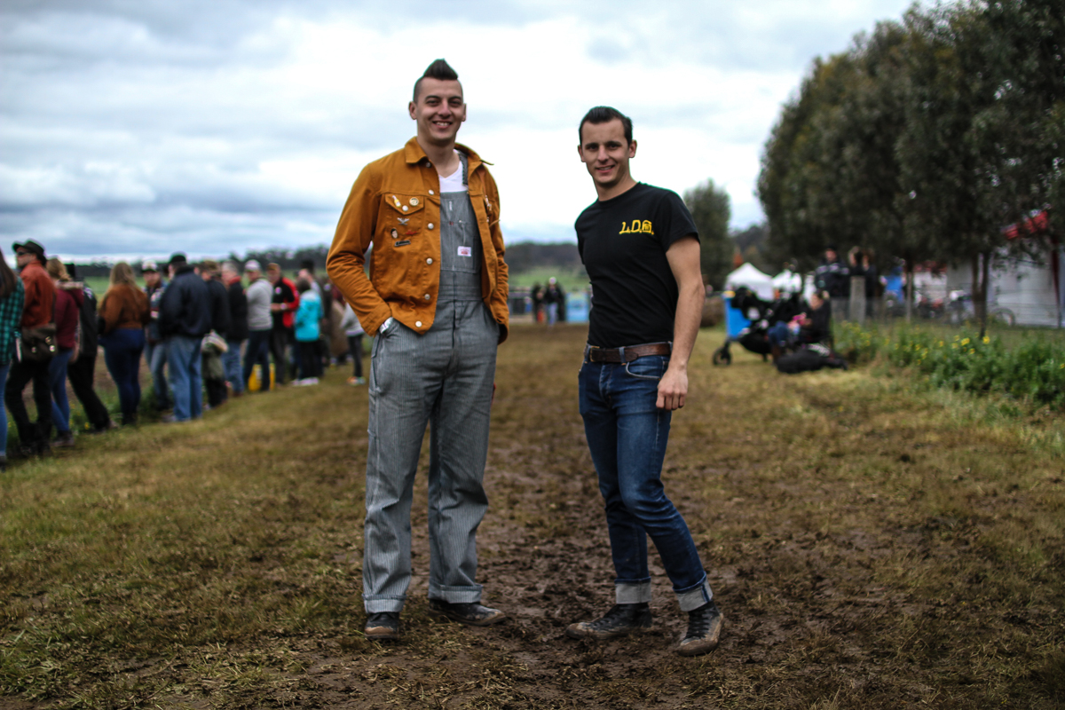 Two men standing side by side on a muddy track.