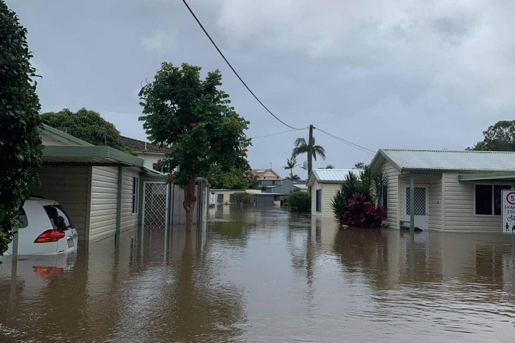 Brown floodwater surrounds caravans and cars.