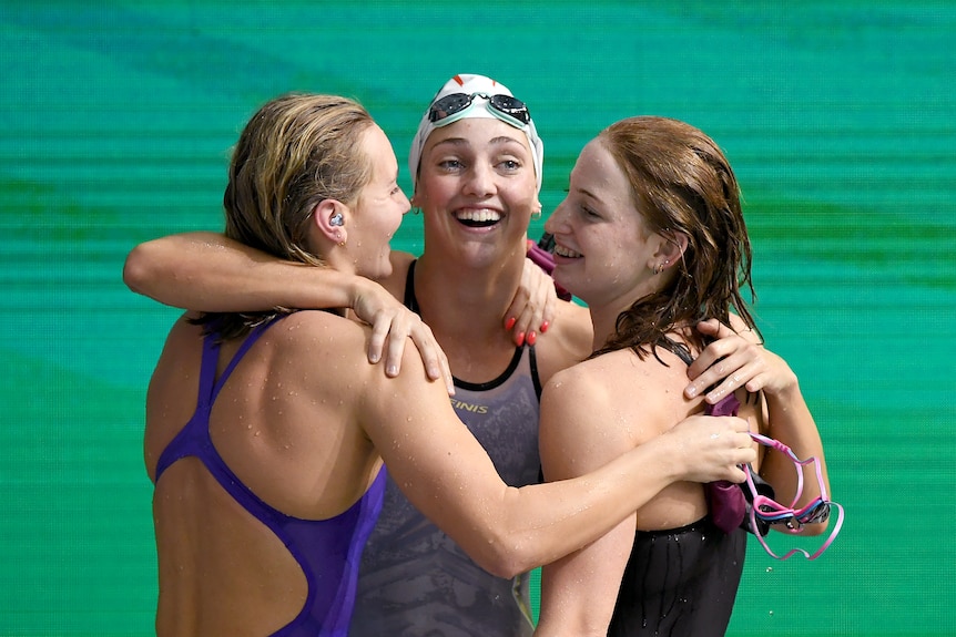 Three young white women in bathers hug