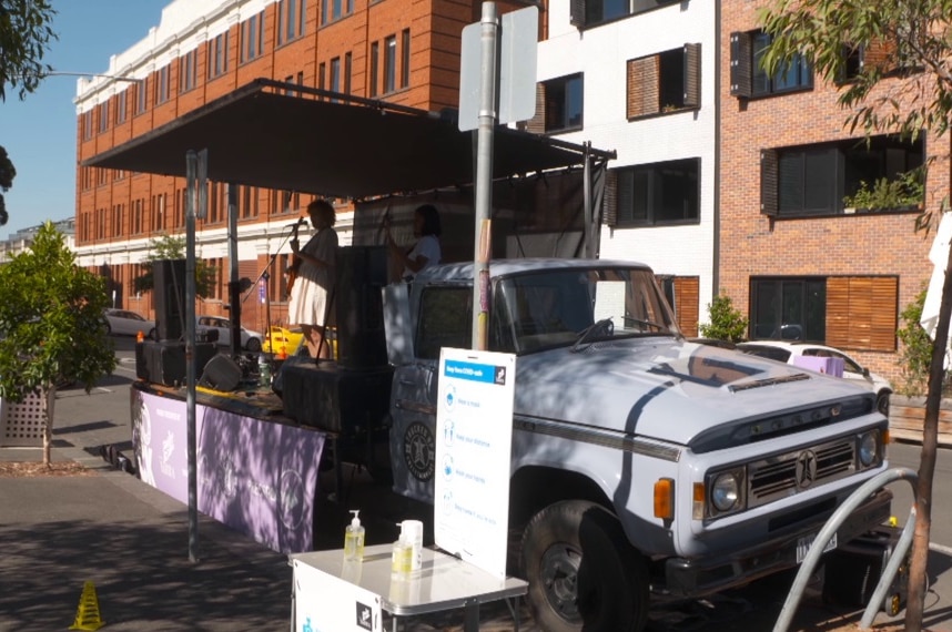 Musicians perform on the back of a truck, which has been turned into a small stage complete with a roof.