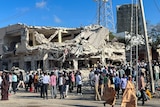 Civilians gather near the ruins of a building at the scene of an explosion 