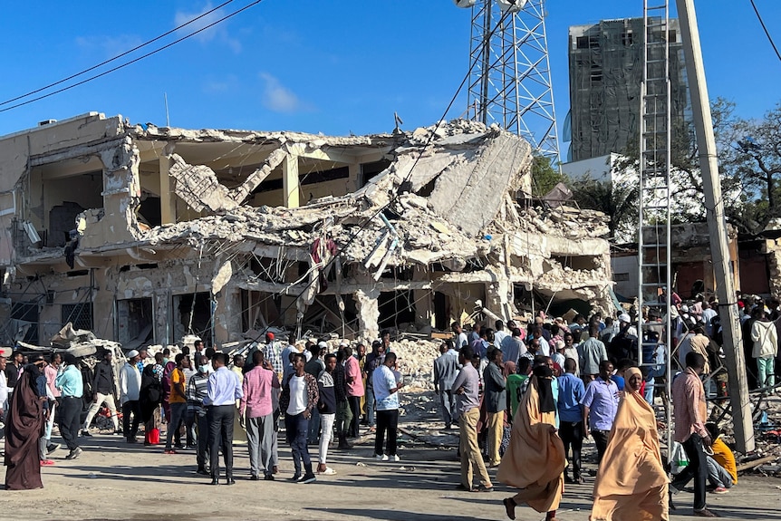 Civilians gather near the ruins of a building at the scene of an explosion 