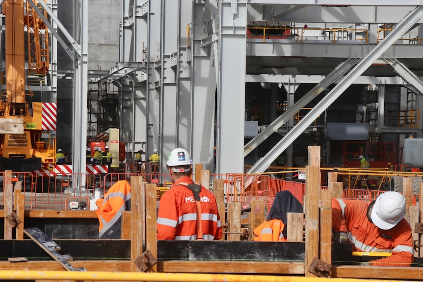 A close-up of a waste-to-energy plant with workers wearing hard hats and high vis.