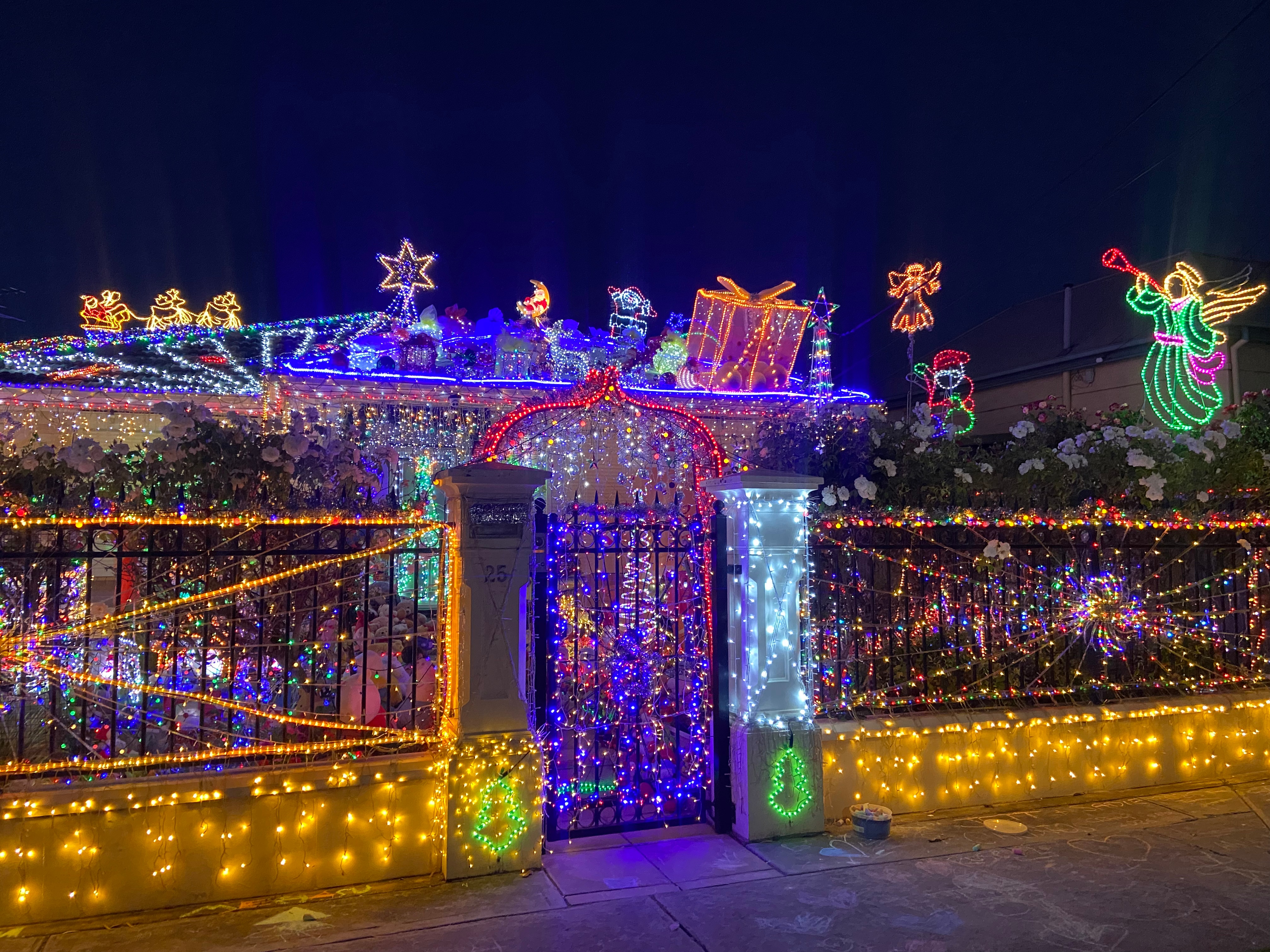Uma grande casa suburbana decorada com luzes de Natal roxas, amarelas e verdes.