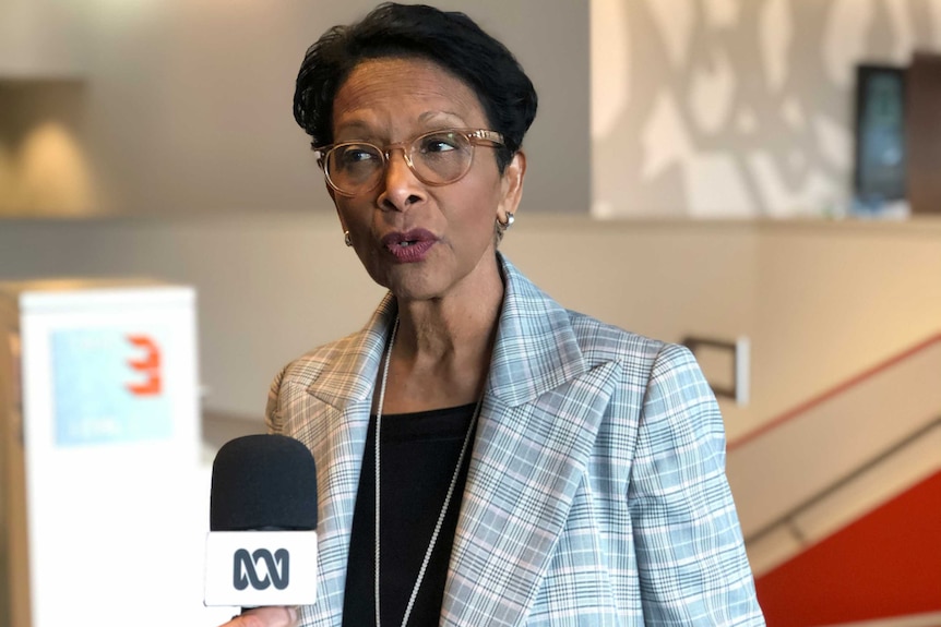 A picture of a woman speaking to an ABC microphone, dressed in a jacket.