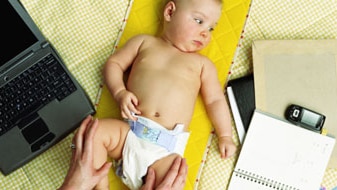 File photo: Baby girl lying by mother, laptop, diary and mobile phone (Getty Creative Images: Photodisc)